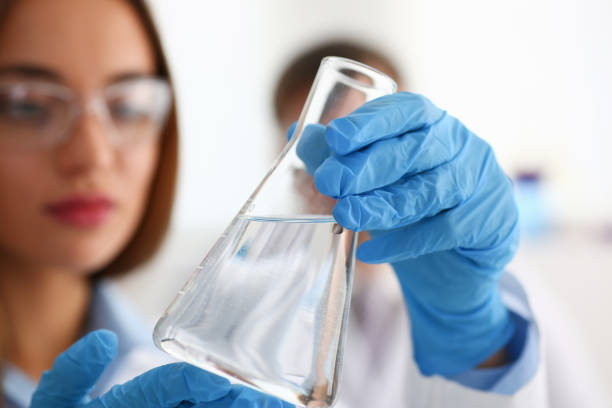 Female technician arms in protective gloves hold Female technician arms in protective gloves hold fluid sample bottle closeup. Medical worker in uniform use reagent tube for virus infection exam or biological toxic reaction test water concept food additive stock pictures, royalty-free photos & images