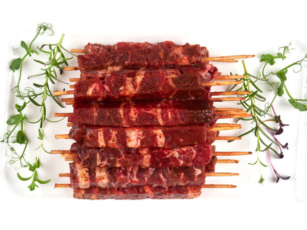 Raw fresh beef and lamb skewers, uncooked Raw fresh beef and lamb skewers, uncooked, on a white plate, garnished with fresh pea shoots and rosemary sprigs rosemary seedlings stock pictures, royalty-free photos & images