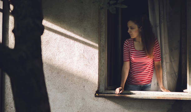 istock Young woman is looking through window 1127344712