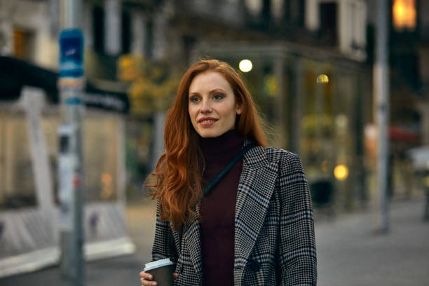 istock Young women with coffee cup looking away in city 1127345351
