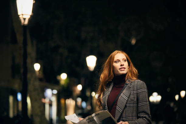 istock Thoughtful woman holding newspaper at night 1127345424