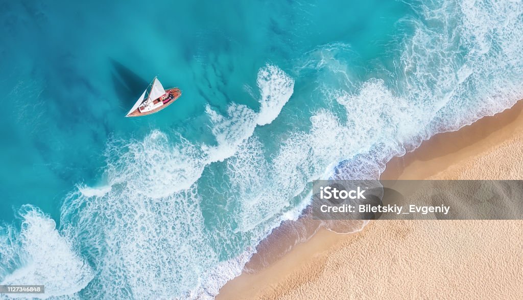 Wellen und Yacht aus Draufsicht. Türkisfarbenes Wasser Hintergrund aus Draufsicht. Sommer-Seelandschaft aus der Luft. Draufsicht von Drohne. Reisen-Bild - Lizenzfrei Strand Stock-Foto