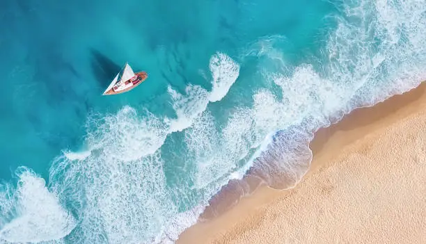 Waves and yacht from top view. Turquoise water background from top view. Summer seascape from air. Top view from drone. Travel-image