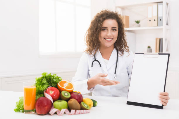 istock Woman nutritionist pointing on blank clipboard at office 1127348001