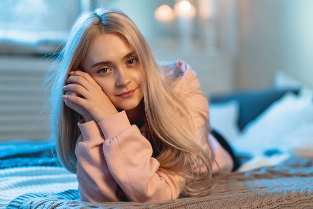istock Young Cute Woman Lying Down On A Bed With Pillows Looking At Camera 1127350646
