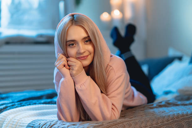 istock Young Cute Woman Lying Down On A Bed With Pillows Looking At Camera 1127350656