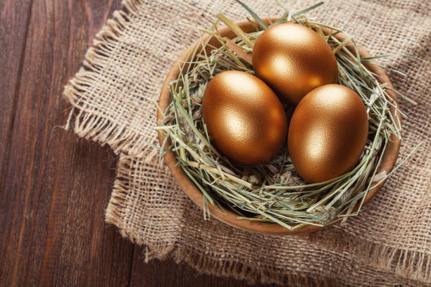 istock Golden eggs in a basket with hay on a rough canvas. Easter composition. 1127351391