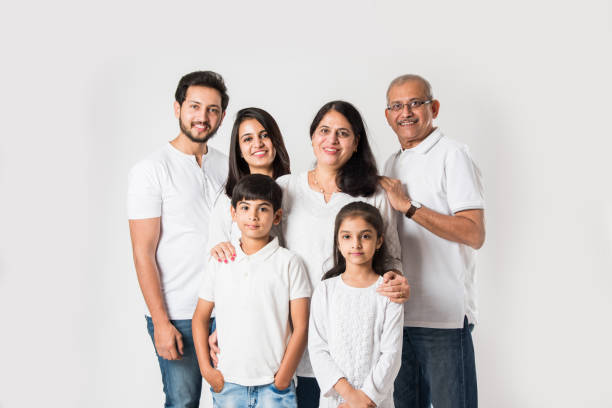 Indian family standing isolated over white background. senior and  young couple with kids wearing white top and blue jeans. selective focus stock photo
