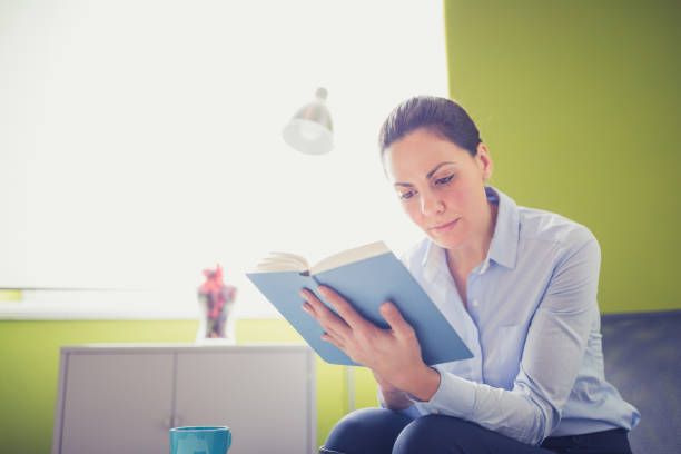 istock Businesswoman reading book in office library 1127355006