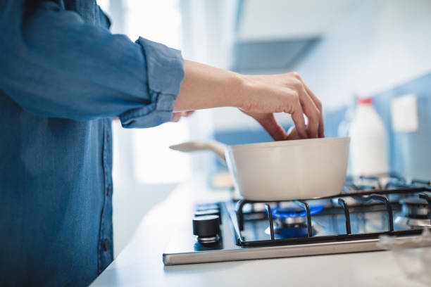 Young woman preparing her breakfast in the kitchen, boiling eggs