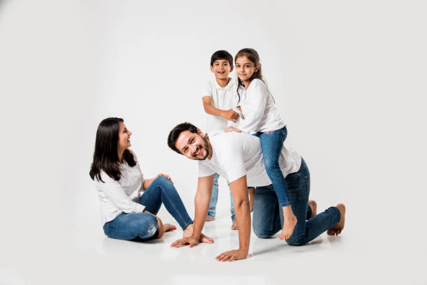 istock happy mad ride on father's back. Indian small girl sitting on Dad's back while mother and brother laughing. selective focus 1127357021