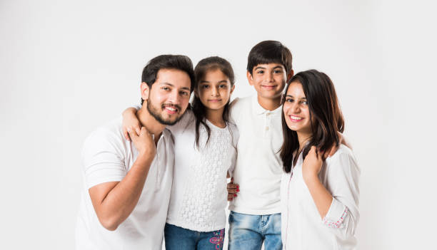 白い背景に分離立って 4 の幸せなインドの家族。ヤング カップル子供白のトップとブルー ・ ジーンズを身に着けています。選択と集中 - women studio shot jeans young adult ストックフォトと画像