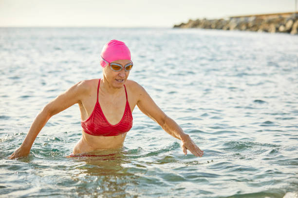 istock Senior female swimmer walking in sea 1127360514