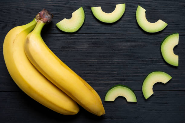 bananas with chopped avocado on a black wooden background