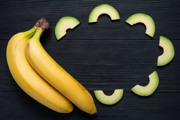 bananas with chopped avocado on a black wooden background