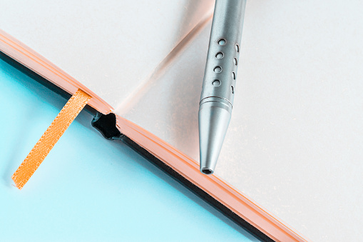 Un cuaderno abierto con un elegante bolígrafo para tomar notas y escribir pensamientos sobre un fondo azul photo