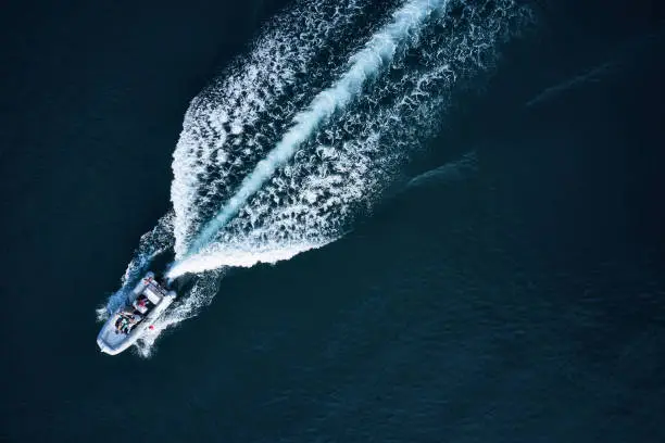 Fast speedboat racing along the open sea leaving white trail. High angle view from drone DJI Mavic 2 Pro (Hasselblad camera).