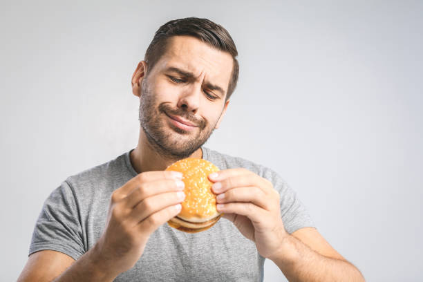 istock Young man holding a piece of hamburger 1127362470