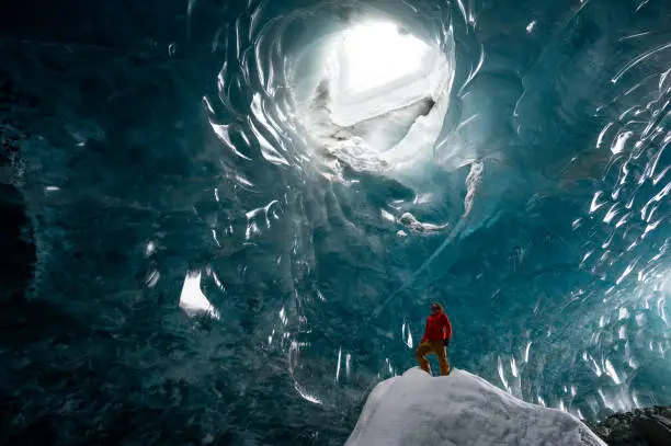 Man exploring a stunning glacial ice cave