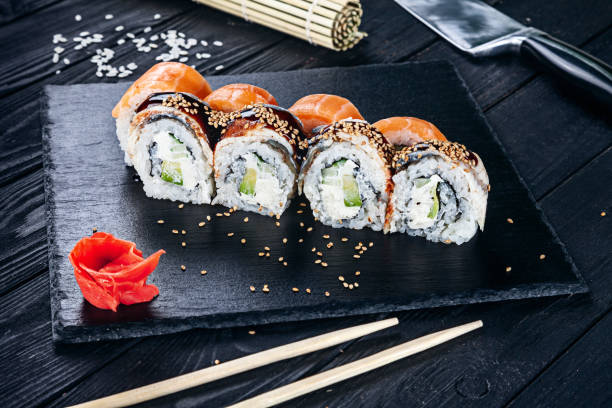 istock Served sushi rolls on black stone with chopsticks. Close up view on sushi on dark background. Traditional japanese cuisine. Restaurant, food menu, recipe, cafe concept. 1127363431