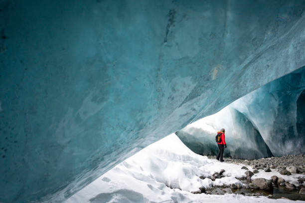 istock Woman exploring a stunning glacial ice cave 1127365558