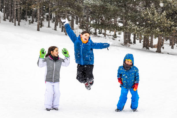 istock Three kids jumping together in a snowy field 1127365648