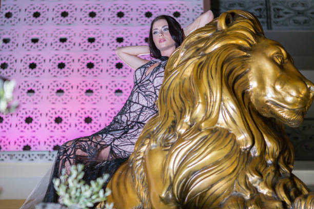 istock Beautiful fashion model sitting on lion statue 1127366955