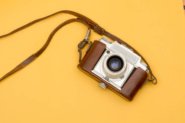 istock Vintage Camera with A Leather Strap Hanging on Yellow 1127370223