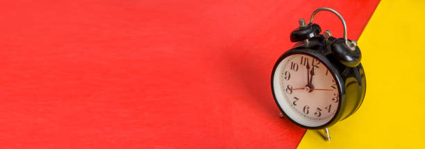 istock Black table clock on yellow and red banner template 1127370243