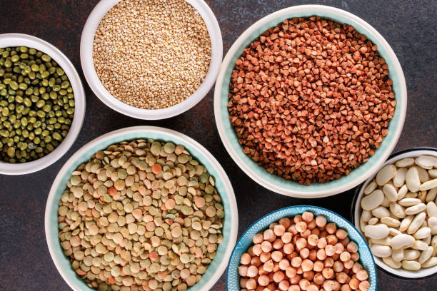 istock Top view on bowls with various raw grains and seeds on a textured dark background. 1127372373
