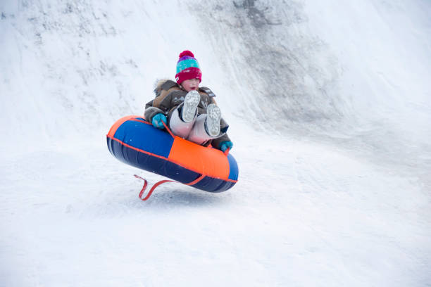 istock Child sledding cheesecake.Sledding off a snow slide 1127373701