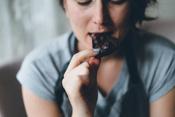 frau essen schokolade - dark choccolate stock-fotos und bilder