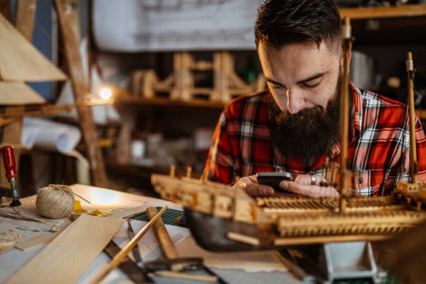istock Young man texting on the phone in his workshop 1127375051