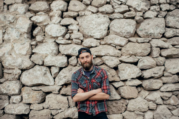 istock Portrait of young handsome hipster man with beard over stone wall looking at camera 1127376356
