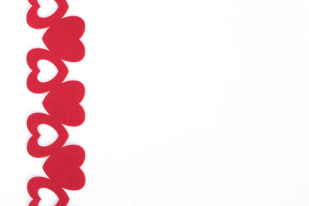 red felt hearts on white paper background with space for text without people abstract