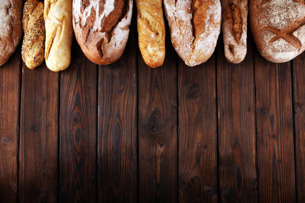 istock Assortment of baked bread and bread rolls on wooden table background 1127377917