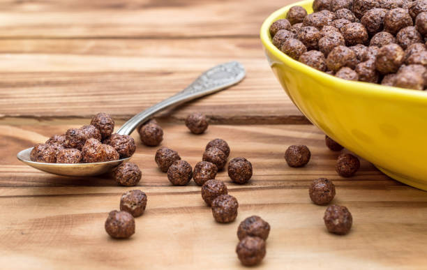 istock Spoon with chocolate corn balls and bowl with chocolate corn balls on wooden table . 1127382721