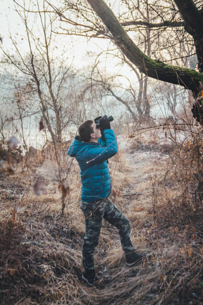 istock Young man  hiking trough forest and watching bird 1127385996