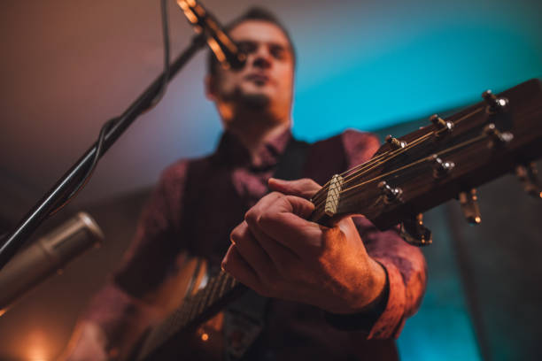 istock Rock musician singing and playing acoustic guitar in studio 1127386018