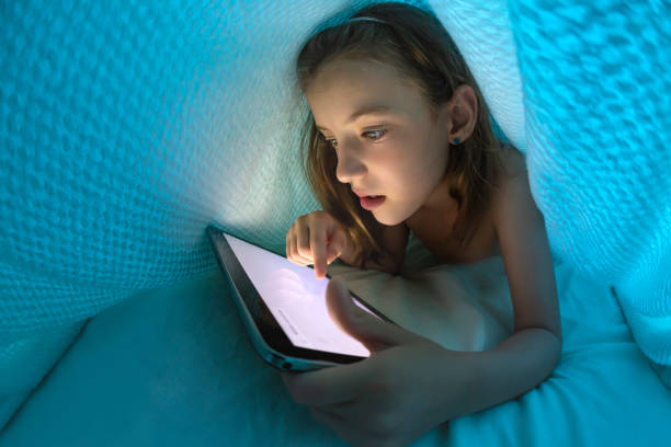 istock Little girl using her digital tablet past her bedtime under a duvet 1127386080