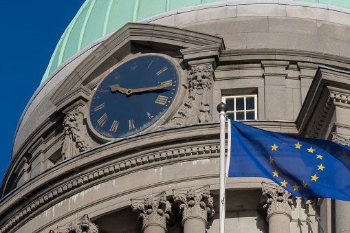 The flag of the European Union flying outside a domed neoclassical building, the Customs House.  Originally constructed in 1791, it was built to the design of James Gandon.  Its purpose was to house government excise officers, policing trade arriving and departing from the port of Dublin, Ireland.  Today, with the expansion of the city, it is located in the city centre, by the banks of the River Liffey.