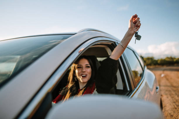 New driver A young woman showing the car keys through the car window driver's license stock pictures, royalty-free photos & images
