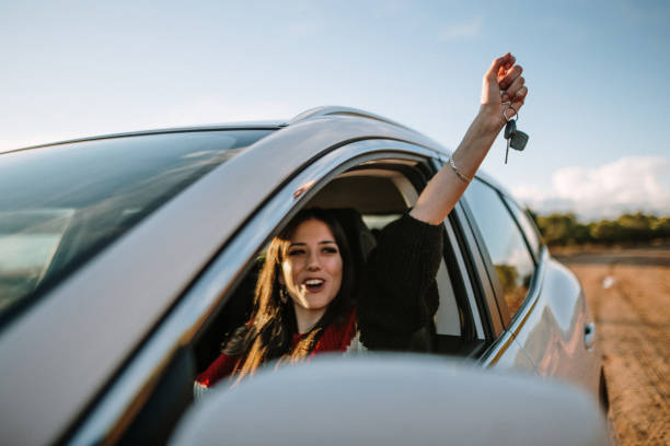 New driver A young woman showing the car keys through the car window driving licence stock pictures, royalty-free photos & images