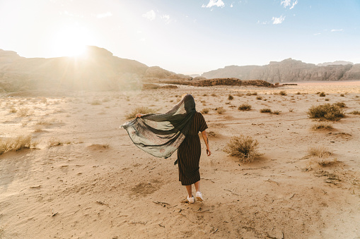 Young Caucasian woman  walking in Wadi Rum desert at sunset