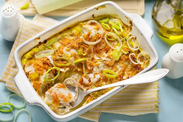 Oven dish gratin with cod fish, grated carrots and leeks