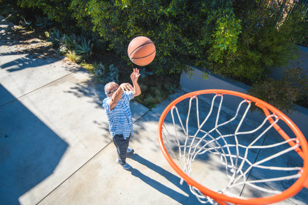 aktiven senior mann werfen basketball in richtung hoop - basketball basketball hoop california southern california stock-fotos und bilder