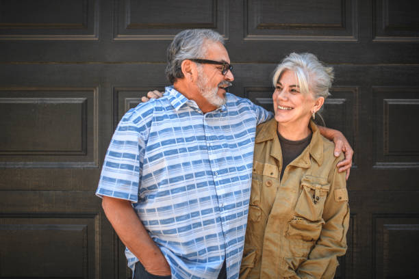 istock Senior couple standing arms around against wall 1127396751