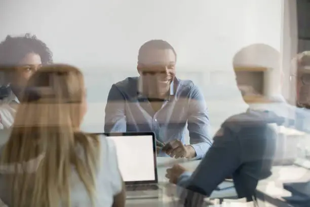 Diverse businesspeople company boss and corporation members discussing planning talking during morning briefing at modern boardroom view through the glass wall, busy working day in creative department