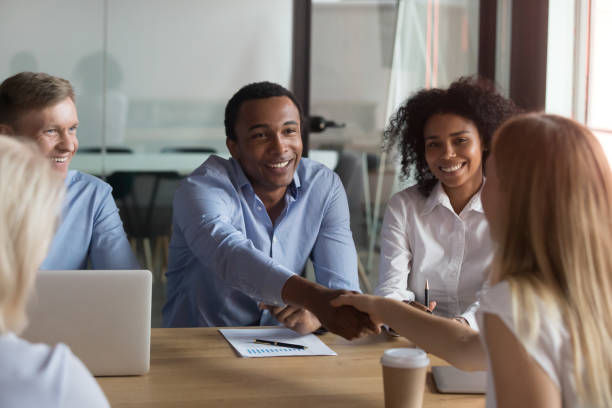 black ceo handshaking with woman financier while sitting at meeting - board room discussion contract agreement imagens e fotografias de stock