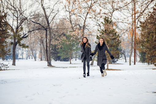 Two young female friends having fun in the snow covered park